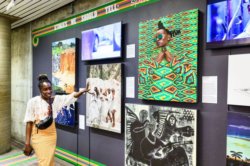 Photo of student Sumayyah Súnmádé Raji MArch ’23 in front of colorful exhibition 