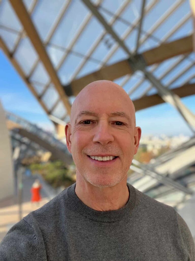 John Mann with structure in background and blue sky