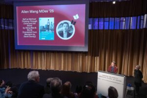 Allen Wang speaks at a Harvard GSD podium in front of a slideshow and audience