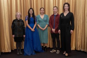 The 2025 Unsung Heroes and jury members smiling in front of a gold curtain