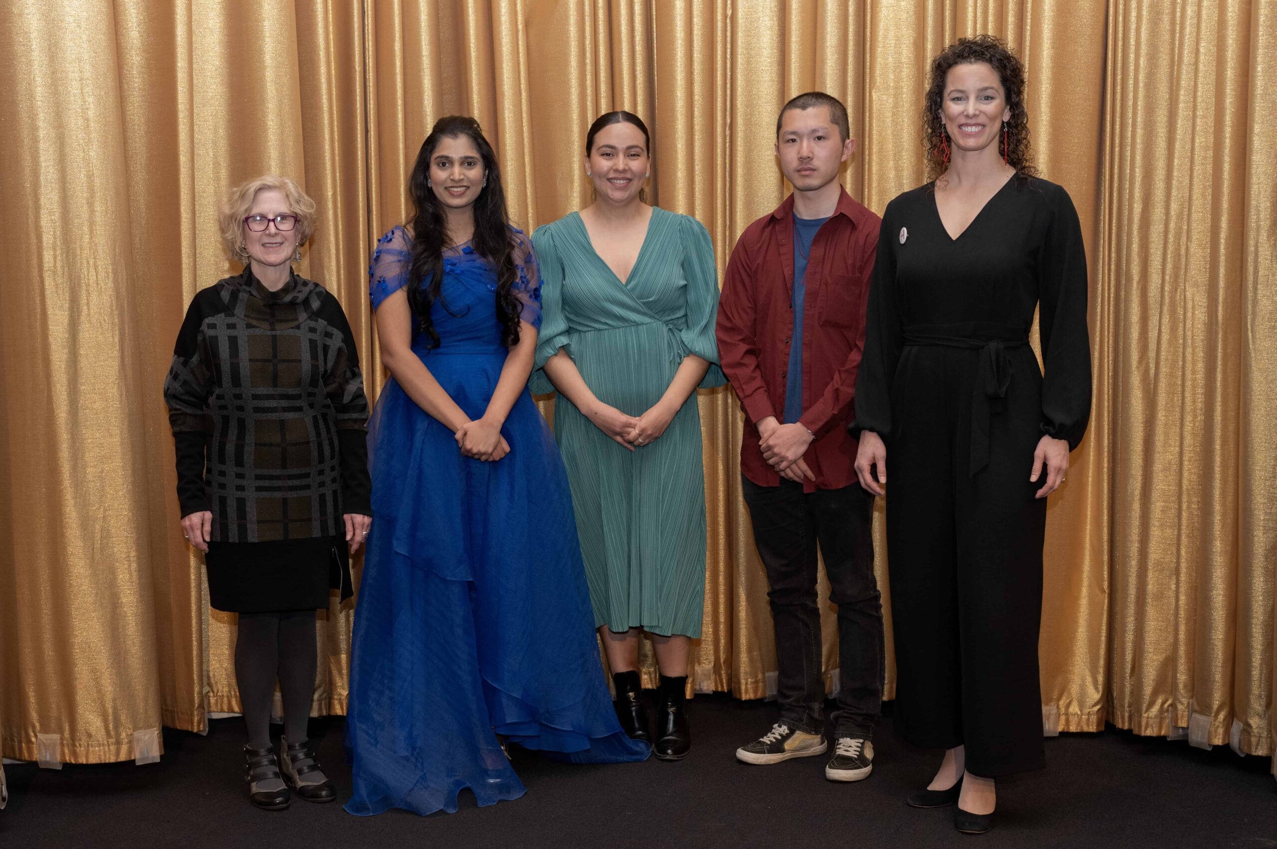 The 2025 Unsung Heroes and jury members smiling in front of a gold curtain