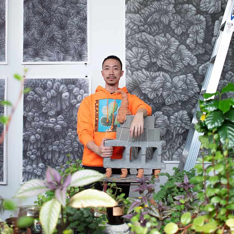 Paul Mok in an orange hoodie in front of a grey background